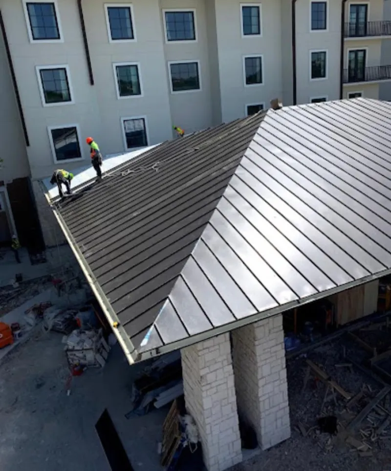 Crew installing standing seam metal roof panels on a commercial project in Malverne